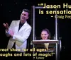 A magician gestures towards his assistant whose body appears to be magically severed at the waist by an illusion box on stage
